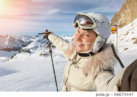 Young adult beautiful happy attractive caucasian smiling skier woman portrait making selfie on mountain peak showing skiing resort panorama breathtaking view. Winter travel adventure welcome concept Young adult beautiful happy attractive caucasian smiling skier woman portrait making selfie on mountain peak showing skiing resort panorama breathtaking view. Winter travel adventure welcome concept 68675447