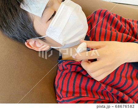 発熱し体温計で熱を測っている小学生の男の子 68676582