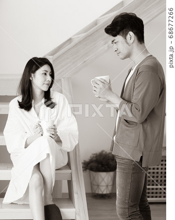 Young asian woman and man at home with cup of coffee in hands in black and white. Young asian woman and man at home with cup of coffee in hands in black and white. 68677266