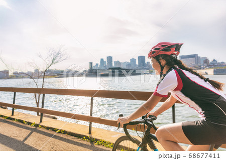 Urban biking girl riding road bike cycling in the city. Happy cyclist with downtown background by the St Lawrence river, Montreal, Canada 68677411