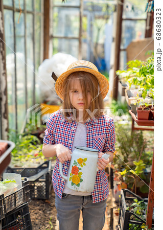 Adorable small girl kid in hat watering seedlings Adorable small girl kid in hat watering seedlings 68680323