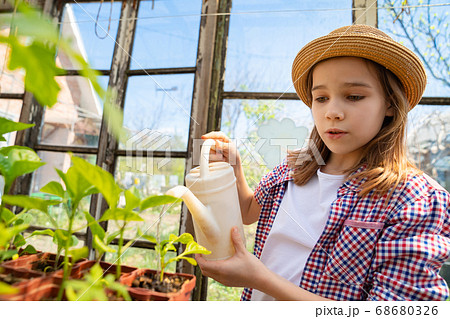 Adorable teen girl kid in hat watering seedlings Adorable teen girl kid in hat watering seedlings 68680326