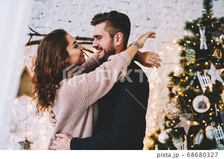Happy caucasian couple in love having fun together near beautiful Christmas tree Happy caucasian couple in love having fun together near beautiful Christmas tree 68680327
