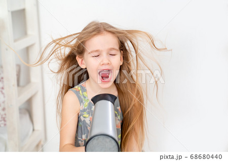 little girl drying her long hair with hair dryer little girl drying her long hair with hair dryer 68680440