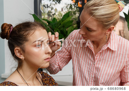 The process of creating makeup. Makeup artist working with a brush on the face of the model. 68680968