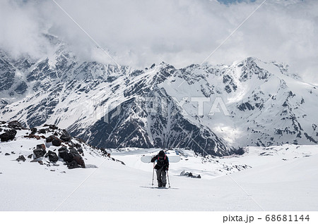 woman snowboarder climbs the mountain through the snow backcountry with a snowboard behind her shoulders. Climb the mountain for freeride woman snowboarder climbs the mountain through the snow backcountry with a snowboard behind her shoulders. Climb the mountain for freeride 68681144