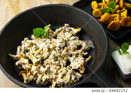 Chanterelle wild mushrooms fried with sour cream sauce in cast iron pan on vintage wooden background 68682252