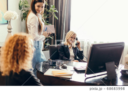 Blonde executive businesswoman doing multitasking work in office. 68683998