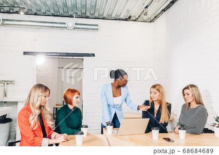 African female boss telling off her female employees, sitting in meeting room. African female boss telling off her female employees, sitting in meeting room. 68684689