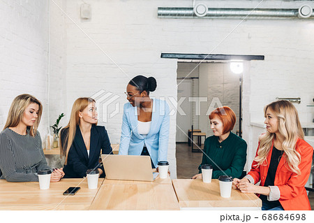 African female boss telling off her female employees, sitting in meeting room. African female boss telling off her female employees, sitting in meeting room. 68684698