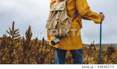 man hiker with backpack walking through the grass meadow 68686574
