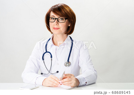 Attractive redhead doctor sitting in office Attractive redhead doctor sitting in office 68689145