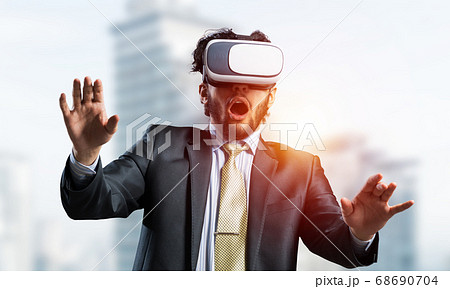 Handsome elegant businessman experiencing impressive virtual reality and business city at backdrop 68690704