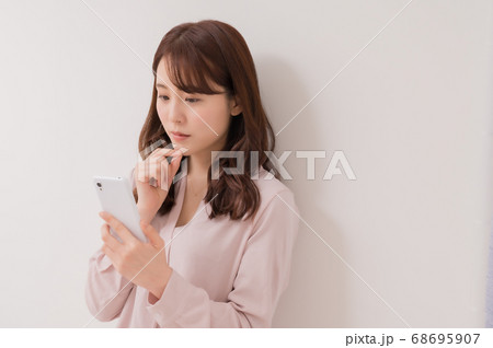 スマホを見て悩む若い女性 68695907