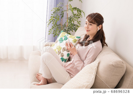 ソファーに座ってスマホを見る若い女性 ソファーに座ってスマホを見る若い女性 68696328