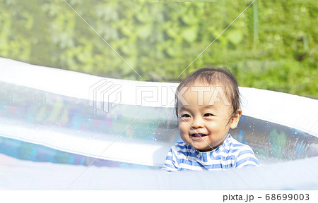 真夏の暑い日に 外でプールで水遊びしている子供 かわいい笑顔の子供の写真素材