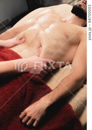 A physiotherapist massager man activates a diaphragm massage to a muscular client male athlete. Close-up. Small depth of field 68700003