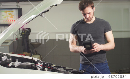 Adult Man Checks the Condition of the Vehicle in a Tire Service Shop. Adult Man Checks the Condition of the Vehicle in a Tire Service Shop. 68702084