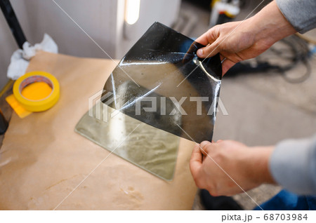 Male worker holds sheet of car tinting Male worker holds sheet of car tinting 68703984
