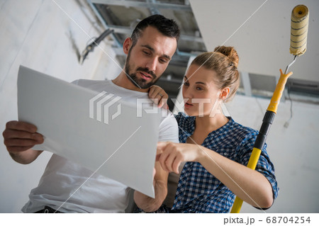 A married couple examines the schema of the house. They smile and talk A married couple examines the schema of the house. They smile and talk 68704254