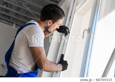 The foreman installs a window frame in the room 68704315