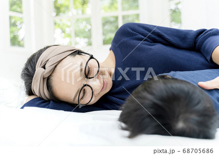 生後5ヶ月の赤ちゃんとベッドでゴロゴロする母親の写真素材