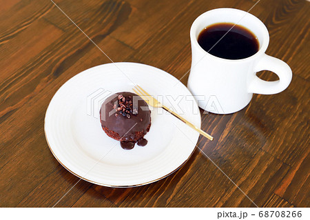 木製テーブルにあるホットコーヒーとチョコケーキ 68708266