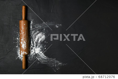 rolling pin and cake flour on black table with 68712076