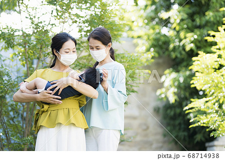 マスクをして生後5ヶ月の赤ちゃんを抱く母と祖母の写真素材