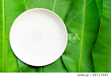 Empty white ceramic plate on banana leaves Empty white ceramic plate on banana leaves 68717693