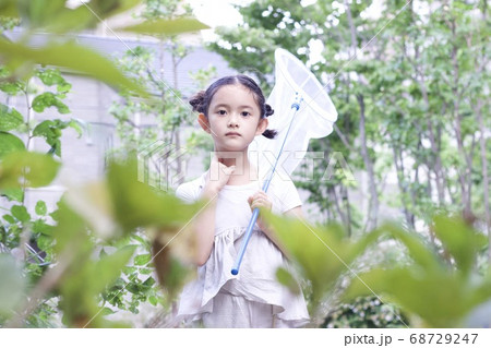 夏休みや夏の暑い日に虫捕り等外で遊ぶ活発な女の子の写真素材