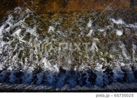 A small waterfall flowing off the side of the road 68730028