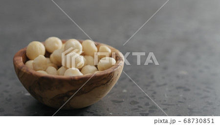shelled macadamia nuts in olive wood bowl on terrazzo surface 68730851