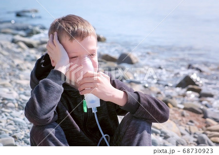 Portrait child boy uses nebulizer inhaler mask to treatment of asthma seaside. Portrait child boy uses nebulizer inhaler mask to treatment of asthma seaside. 68730923