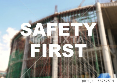 The word SAFETY FIRST is written clearly and against the background of the image of a worker installing a scaffolding. The image has been blurred. The word SAFETY FIRST is written clearly and against the background of the image of a worker installing a scaffolding. The image has been blurred. 68732514