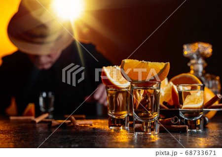 Glasses of tequila with orange and cinnamon sticks Glasses of tequila with orange and cinnamon sticks 68733671