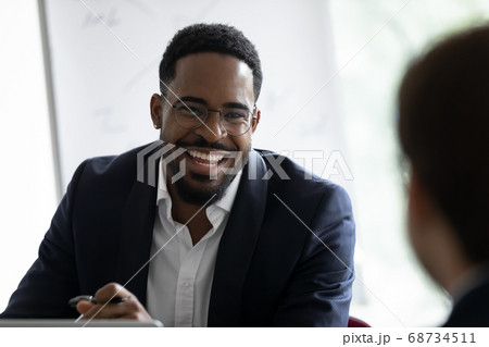 Smiling african businessman communicating with client in office Smiling african businessman communicating with client in office 68734511