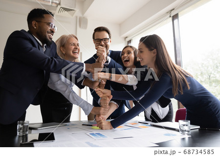 Happy employees coworkers stacking fists together showing corporate spirit Happy employees coworkers stacking fists together showing corporate spirit 68734585