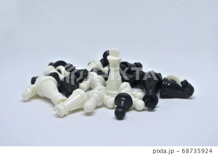 Selected focused on black and white chess pieces all together arranged randomly on white background.  68735924