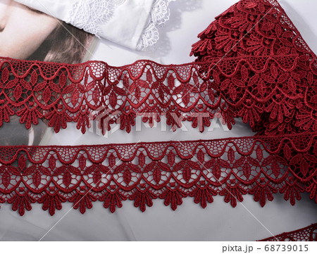 Tapes of red vinous gentle guipure, beauty lace fabric on light background 68739015