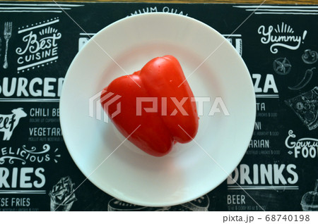 Red bell pepper on white food plate on black 68740198