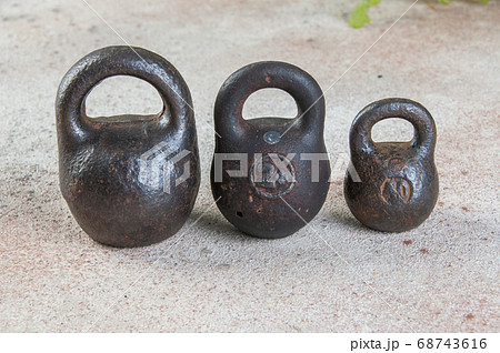 Three antique iron weights for scales on concrete 68743616