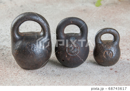 Three antique iron weights for scales on concrete 68743617