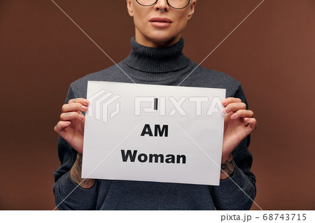 Midsection of female with tattooes showing paper saying that she is a woman Midsection of female with tattooes showing paper saying that she is a woman 68743715