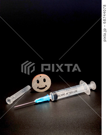 An empty medical syringe with a needle and a smiley face with a smile on a black background 68744078