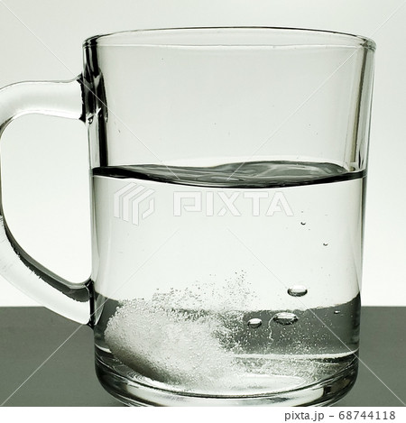 large glass of water and a fast-dissolving tablet, medicine in a glass of water 68744118