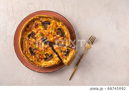 Traditional French pie quiche with mushrooms and cheese with a piece cut off on a plate, next to a Traditional French pie quiche with mushrooms and cheese with a piece cut off on a plate, next to a 68745092