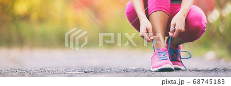 Running shoes runner woman tying laces for autumn run in forest park panoramic banner copy space. Jogging girl exercise motivation heatlh and fitness. Running shoes runner woman tying laces for autumn run in forest park panoramic banner copy space. Jogging girl exercise motivation heatlh and fitness. 68745183