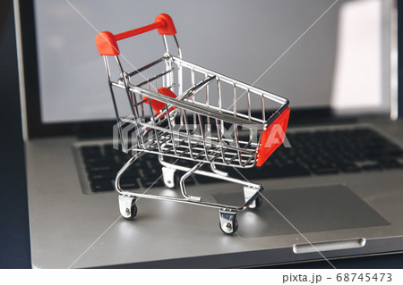 Online shopping concept. Shopping cart, small boxes, laptop on the desk 68745473