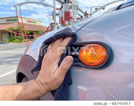 Man's hand cleaning the car with black microfiber cloth. Hand wipe down surface of car 68745937